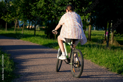 Wallpaper Mural A person rides a bike down a paved path. Trees line the sides of the path in a grassy area of the park. It is a sunny day in the park, ideal for a relaxing ride Torontodigital.ca
