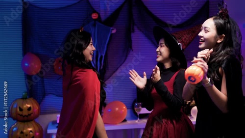 Joyful young asian women in spooky costumes dancing and having fun at a halloween party. Friends celebrating a night event together