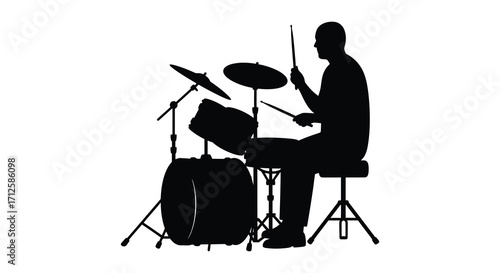 A drummer intensely playing his drum set in striking silhouette