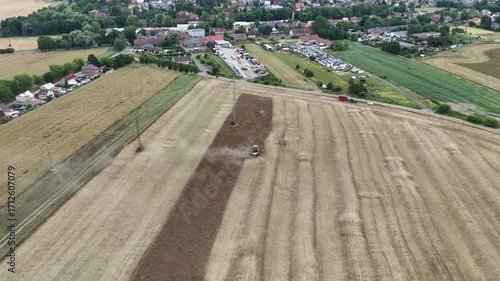 Aerial drone footage of a combine harvester cutting a golden wheat field, showcasing modern agriculture, grain harvest, rural landscape, and seasonal farming productivity.