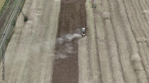 Aerial drone footage of a combine harvester cutting a golden wheat field, showcasing modern agriculture, grain harvest, rural landscape, and seasonal farming productivity.