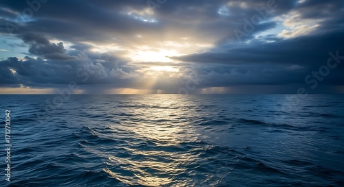Sunlight streams through dark clouds over a vast, choppy ocean