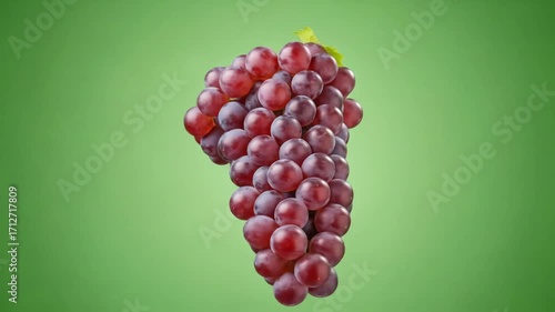 A bunch of plump red grapes with fresh leaves is showcased against a vibrant green background.
