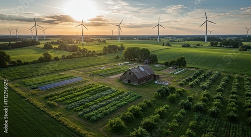 A sprawling rural landscape showcasing a working farm, solar panels, and wind turbines, bathed in the golden light of a tranquil sunset.