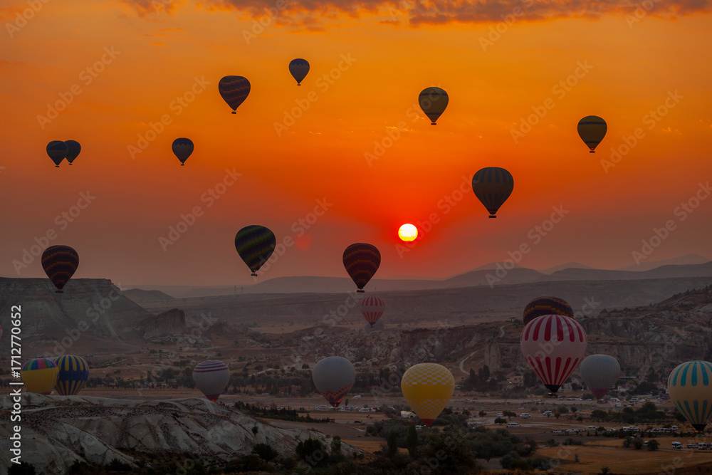 Naklejka premium Hot air balloon flying over rocky landscape at sunrise in Cappadocia. Turkey