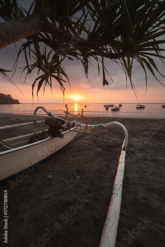 Traditional Fishing Boat at Sunrise on Black Sand Beach in Lombok, Indonesia