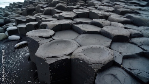 Dark basalt columns on black sand beach