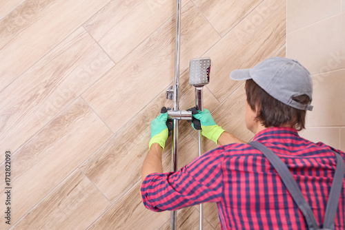 Plumber installing new shower head and rail in bathroom, renovation and home improvement concept