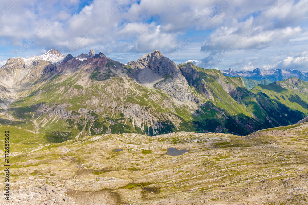 Obraz premium Alps mountains scenic landscape in summer. Austrian Alps scenery trekking path among the high mountain peaks in summer. Green mountain valleys with rocky peaks and lake in the Alps in Austria