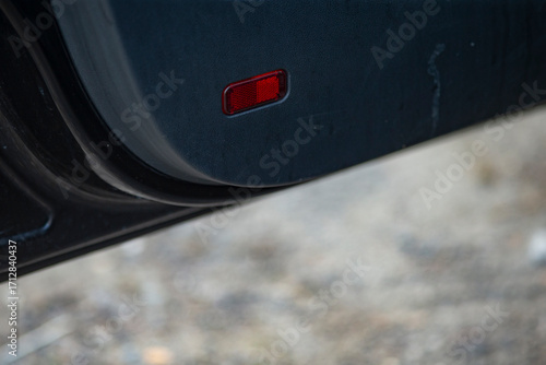 A close-up view showcasing the detail of a car's tail light and bumper, emphasizing sleek automotive design and safety features.