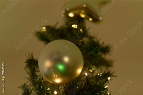 Close-up of a beautifully decorated Christmas tree featuring a shimmering ball ornament and warm lights, perfect for festive celebrations.