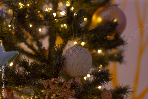A close-up view of a festive Christmas tree adorned with lights and ornaments, creating a cozy and cheerful atmosphere.