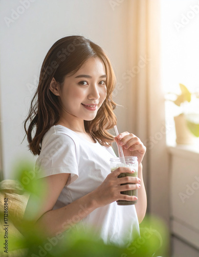 Young woman drinking smoothie in cozy living room, healthy lifestyle