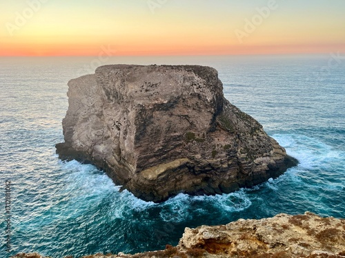 Énorme rocher émergeant de l’eau turquoise au coucher de soleil en Algarve – falaises et vagues pittoresques