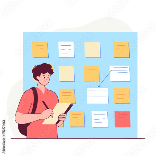 Young man writing notes while standing in front of sticky wall  