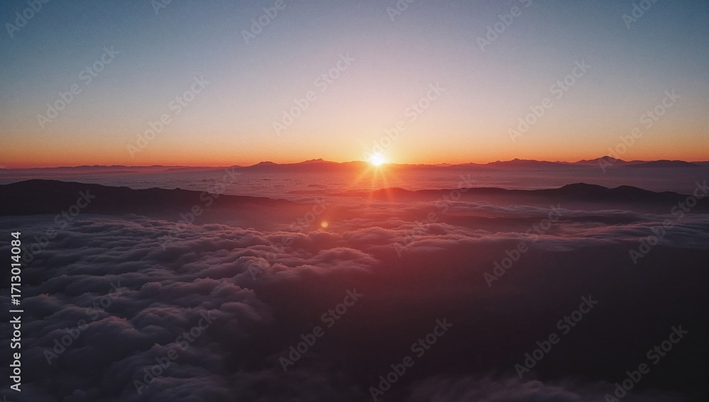 Obraz premium View from above showing a vivid sunset over distant peaks surrounded by soft, white clouds