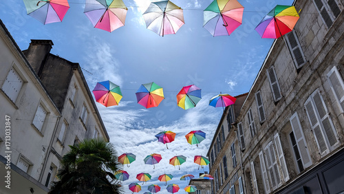 Colorful umbrellas hanging above a street as decoration in Rochefort, Charente-Maritime, France under blue sky.
