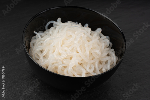 Shirataki or konnyaku pasta in black bowl. Konjak jelly noodles, Japanese zero calorie sirataki