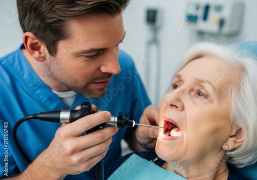 Focused Male Doctor Performs Oral Examination on Senior Woman with an Endoscope Camera.