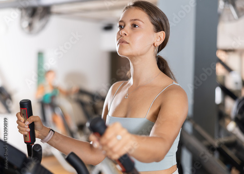 Quadro su tela Active athlete young woman engaged in intensive high interval training on ellipsoid simulator
