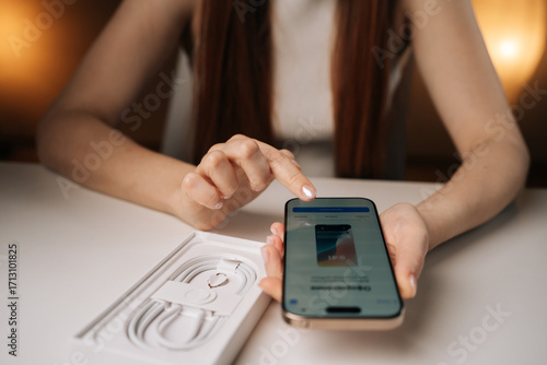 Ufa, Russia - 17 August 2025. Woman unpacking new iPhone 16 pro, examining sleek device and innovative features while setting up smartphone for very first time, unpacking process of latest smartphone