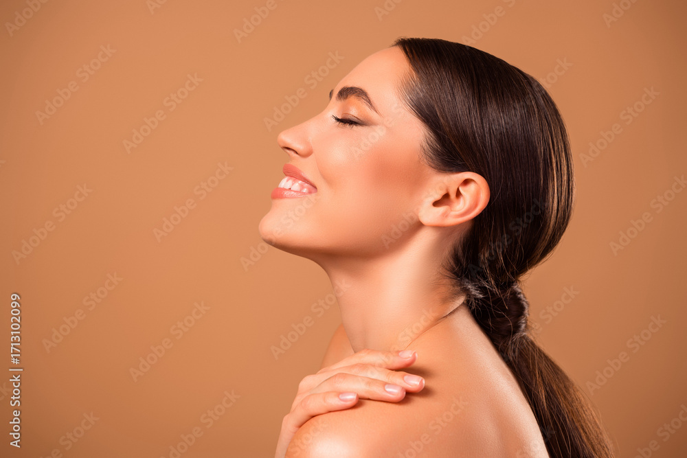 Fototapeta premium Beautiful young woman posing on warm beige background showcasing flawless skin and natural beauty