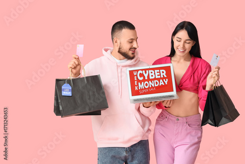 Young couple with shopping bags, credit cards and laptop on pink background. ...