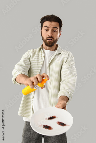 Young man spraying cockroac...