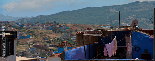 View of Chefchaouen hillside houses with laundry and Rif mountains, Morocco