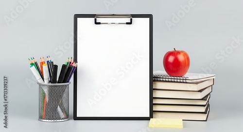 Classroom setup Clipboard with blank paper, apple on books, pens in holder on gray background. Teacher's desk concept, still life arrangement.