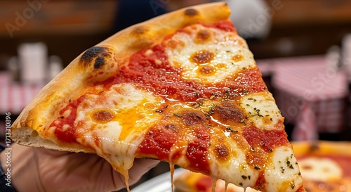 Hand holding a classic New York style cheese pizza slice with melted mozzarella.