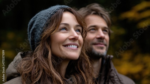 A happy couple enjoys nature, sharing smiles amidst a serene, colorful autumn landscape.