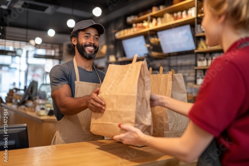 A delivery driver picking up bags of food from the counter Staff hands them over quickly The mood feels fast and professional
