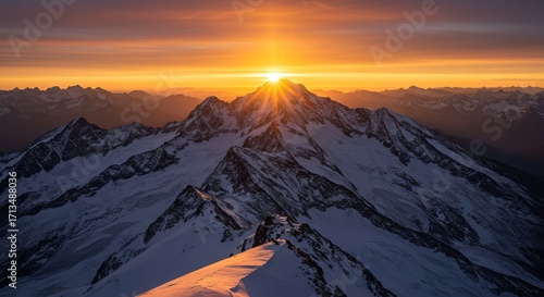 Snowy peaks meet a fiery sky Sunburst piercing mountain crown