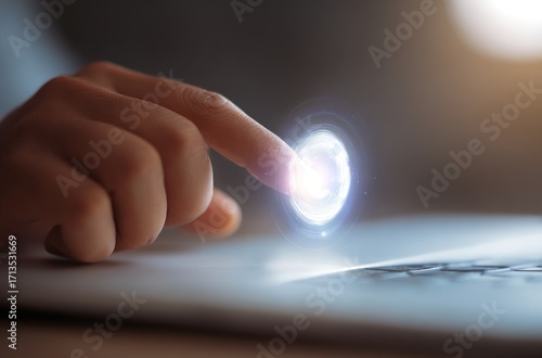 Close up shot A finger touching an illuminated, swirling, digital interface over a laptop surface. Soft, blurred backdrop and side lighting