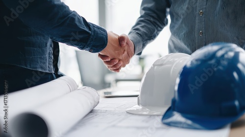 Two professionals shaking hands in a workspace, symbolizing collaboration and partnership in construction.