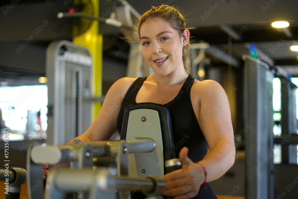 Fototapeta premium Woman smiling while working out on gym machine