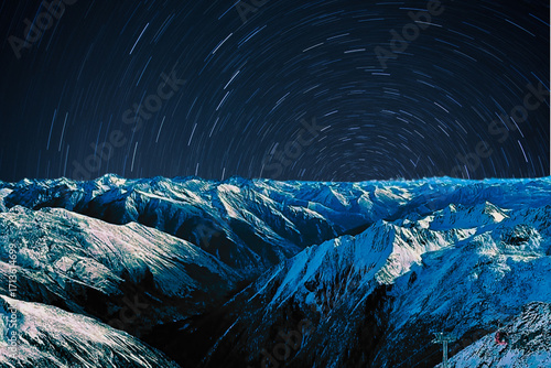 night view of snowy mountain range and milky way. starry night sky with stars and moon. beautiful landscape with snowy mountain peaks in winter night.