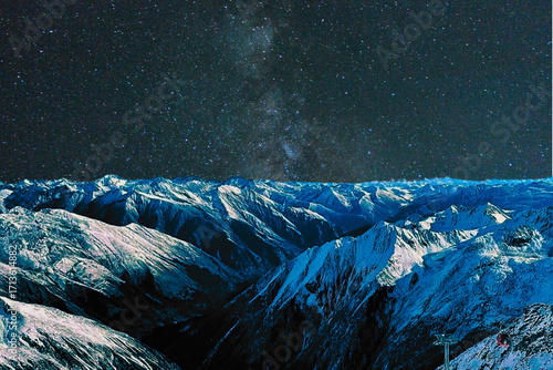 night view of snowy mountain range and milky way. starry night sky with stars and moon. beautiful landscape with snowy mountain peaks in winter night.