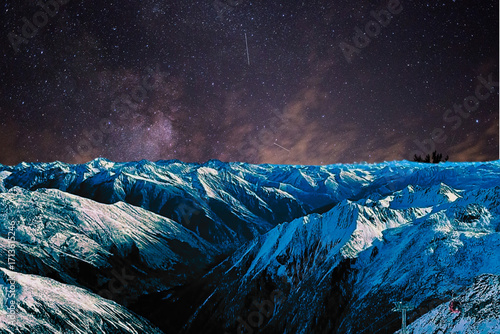 night view of snowy mountain range and milky way. starry night sky with stars and moon. beautiful landscape with snowy mountain peaks in winter night.