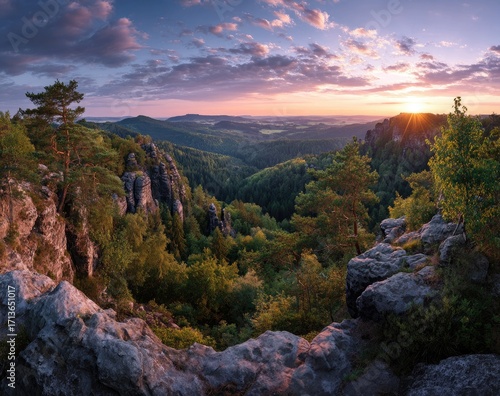 Panoramic sunset view from rocky mountaintop. Lush forest valleys and distant hills below