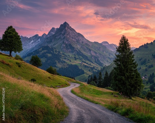 Winding mountain road at sunset. Lush valley, peaks, and colorful sky