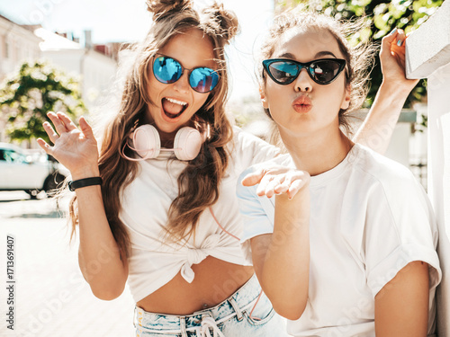 Portrait of two young beautiful smiling hipster female in trendy summer white t-shirt clothes.Sexy carefree women posing on street background. Positive models having fun, hugging and going crazy