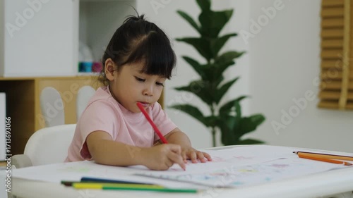 toddler baby girl training to drawing with colored pencil on a desk at home