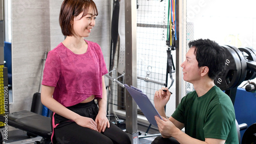 ジムで男性インストラクターと話す若い女性