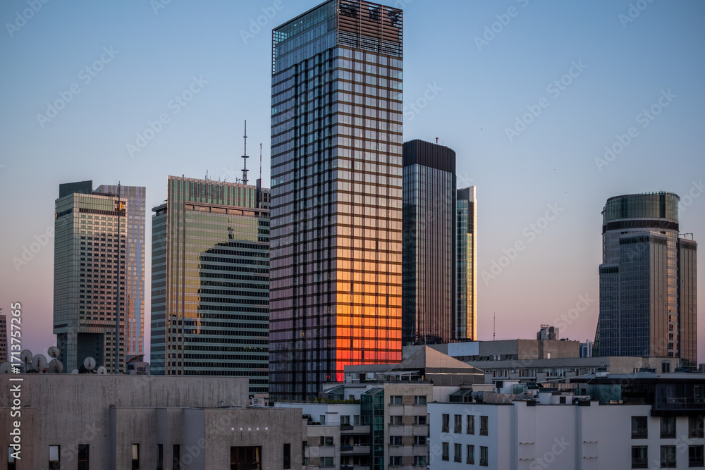 Fototapeta premium Warsaw, Poland, Skyscraper reflecting sunset hues, surrounded by modern urban architecture, showcasing glass facades and vibrant city lights, embodying contemporary urbanism and architectural beauty