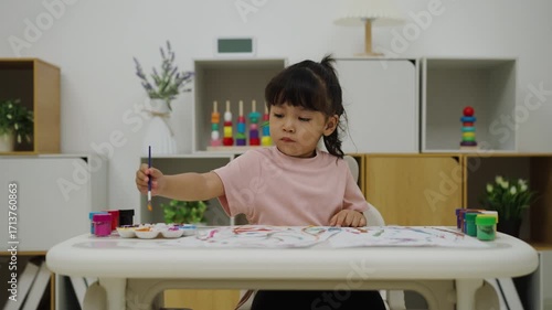 happy toddler girl painting watercolor in paper at home