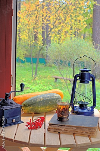 Autumn composition with zucchini, glass of tea, old book and kerosene lamp. Autumn retro home decor