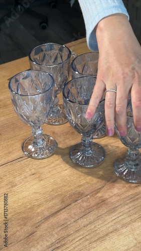 A set of glass goblets. A woman unboxing and reviewing stemmed glass goblets. Vertical video.  Close-up.