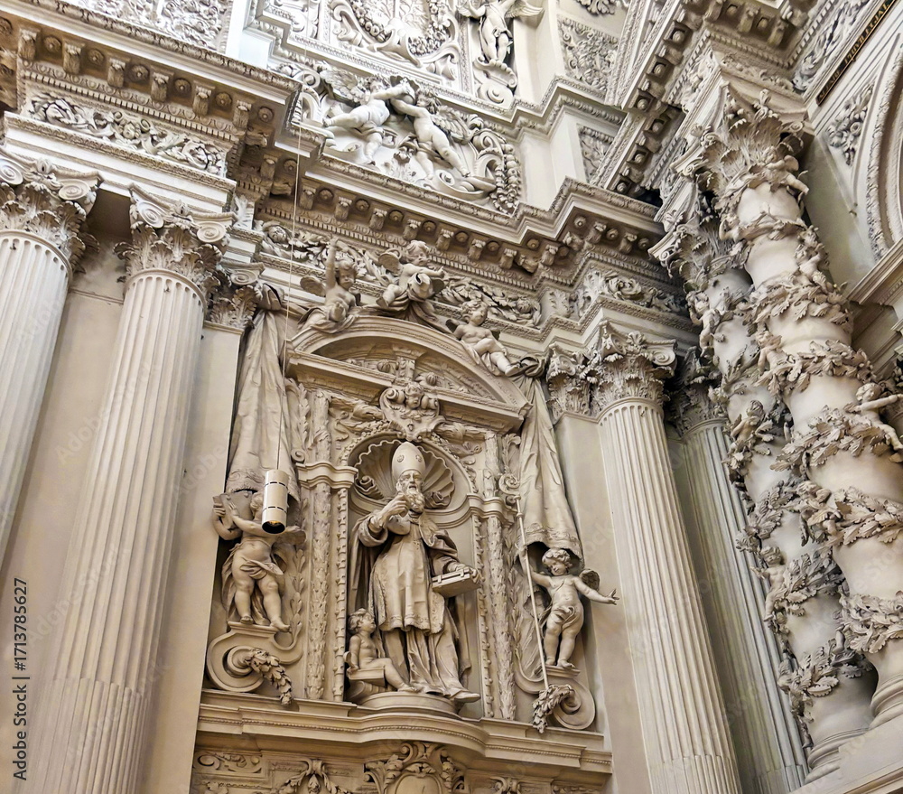 Fototapeta premium A view from below of the amazing masterpieces of sculptural art and stone carving art that decorate the premises of the Theatinerkirche with angels, archbishops and saints.